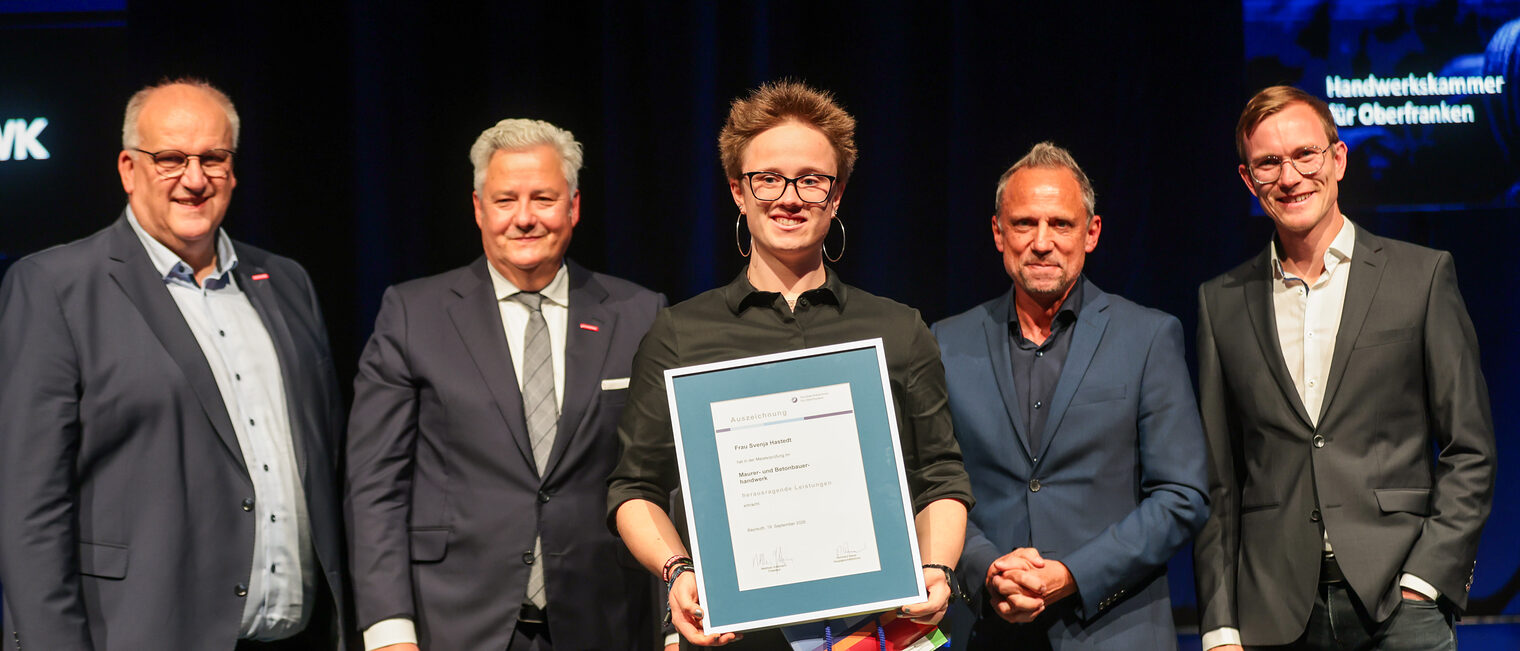 Jungmeisterin Svenja Hastedt präsentiert ihre Ehrenurkunde mit Gratulanten auf der Bühne.