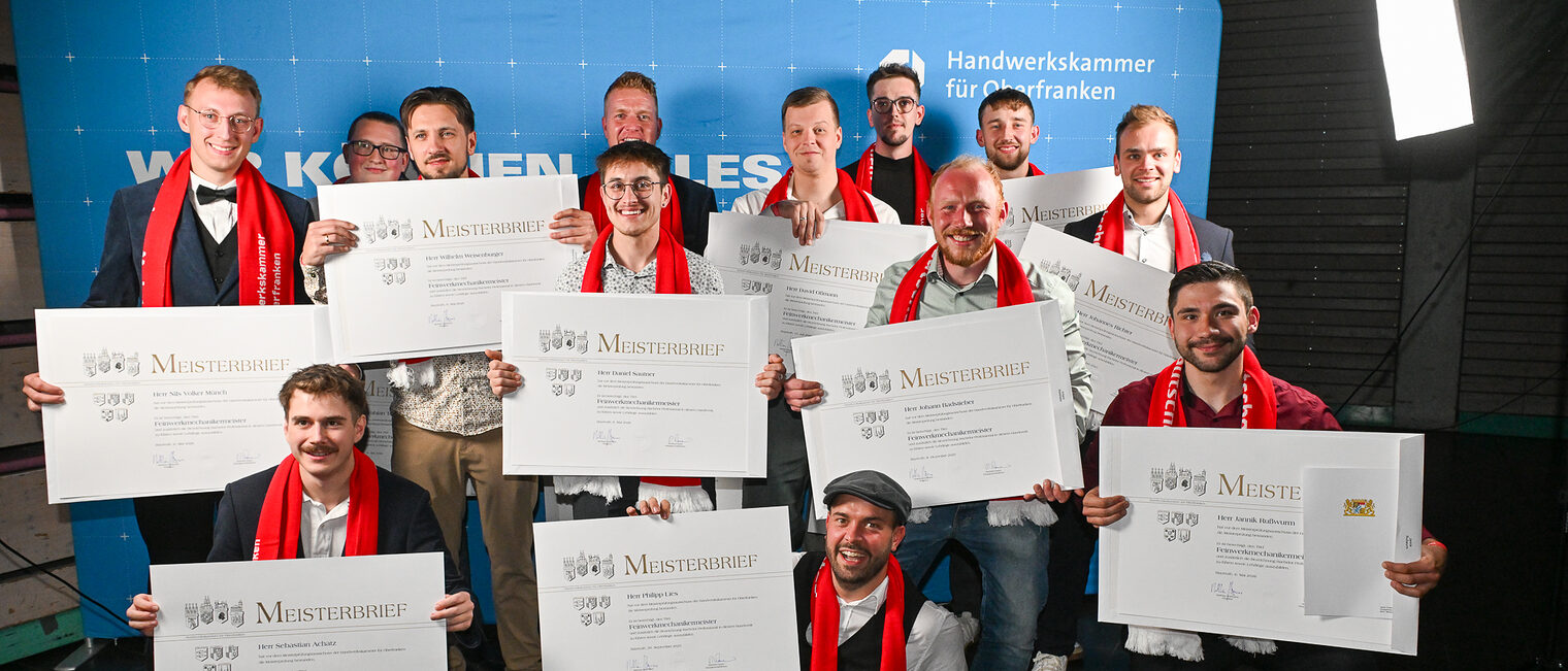 Die Jungmeisterinnen aus dem Feinwerkmechanikerhandwerk posieren vor einer Fotowand.