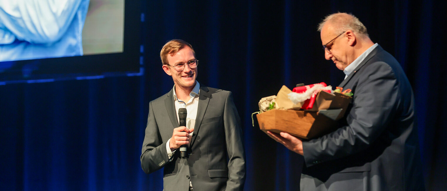 Benedikt Doll nimmt einen Geschenkkorb von HWK-Hauptgeschäftsführer Reinhard Bauer in Empfang.