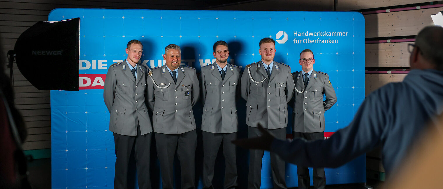 Die Jungmeisterinnen der Bundeswehr posieren für ein Gruppenbild vor einer Fotowand.
