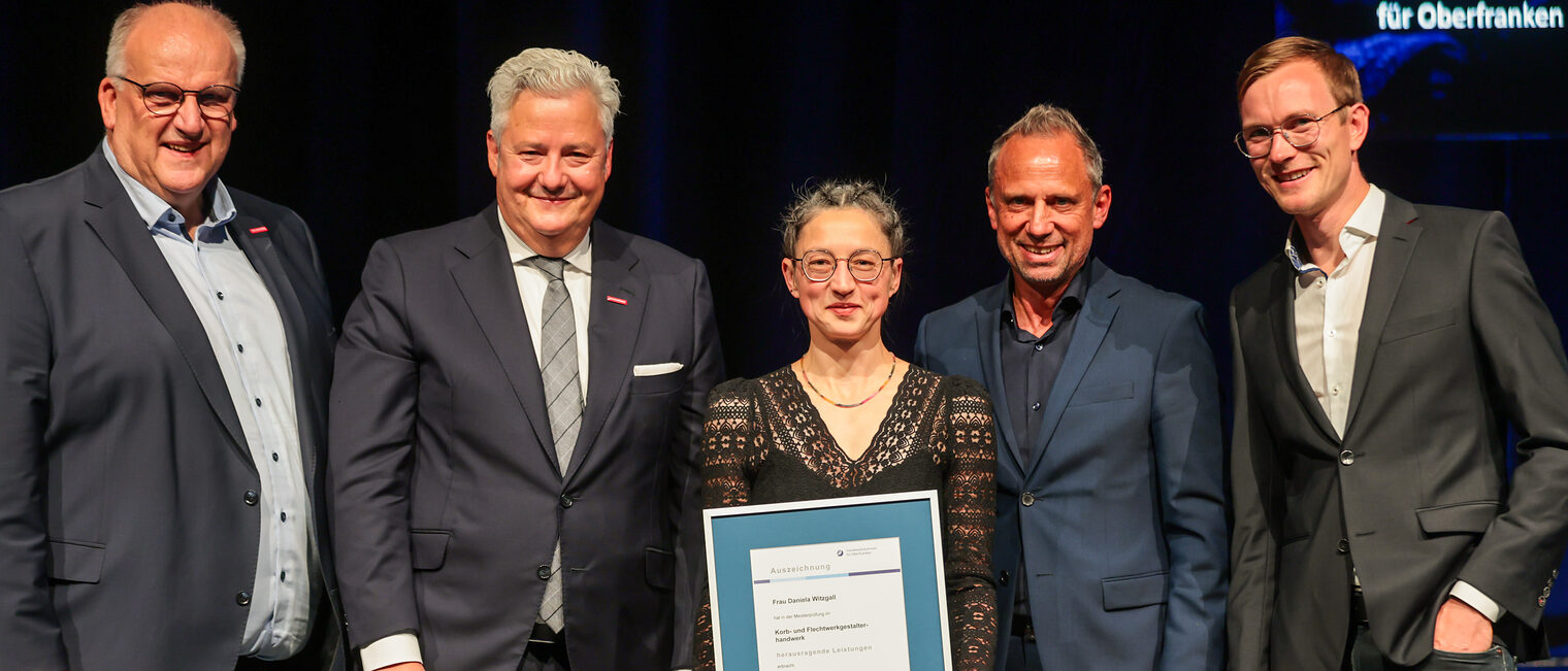 Die beste Jungmeisterin Daniela Witzgall präsentiert ihre Ehrenurkunde mit Gratulanten auf der Bühne. 