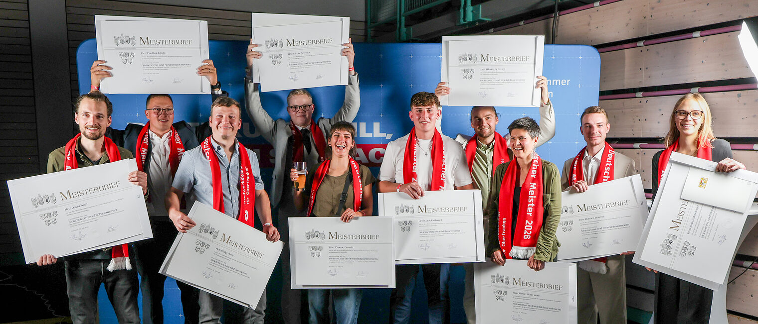 Jungmeisterinnen und -meister stehen für ein Gruppenbild vor einer Fotowand.