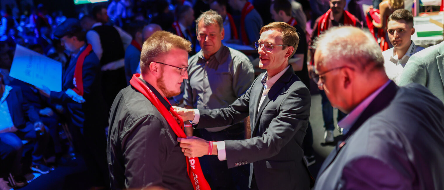 Benedikt Doll und Reinhard Bauer übergeben einen Meisterschal an einen neuen Meister.