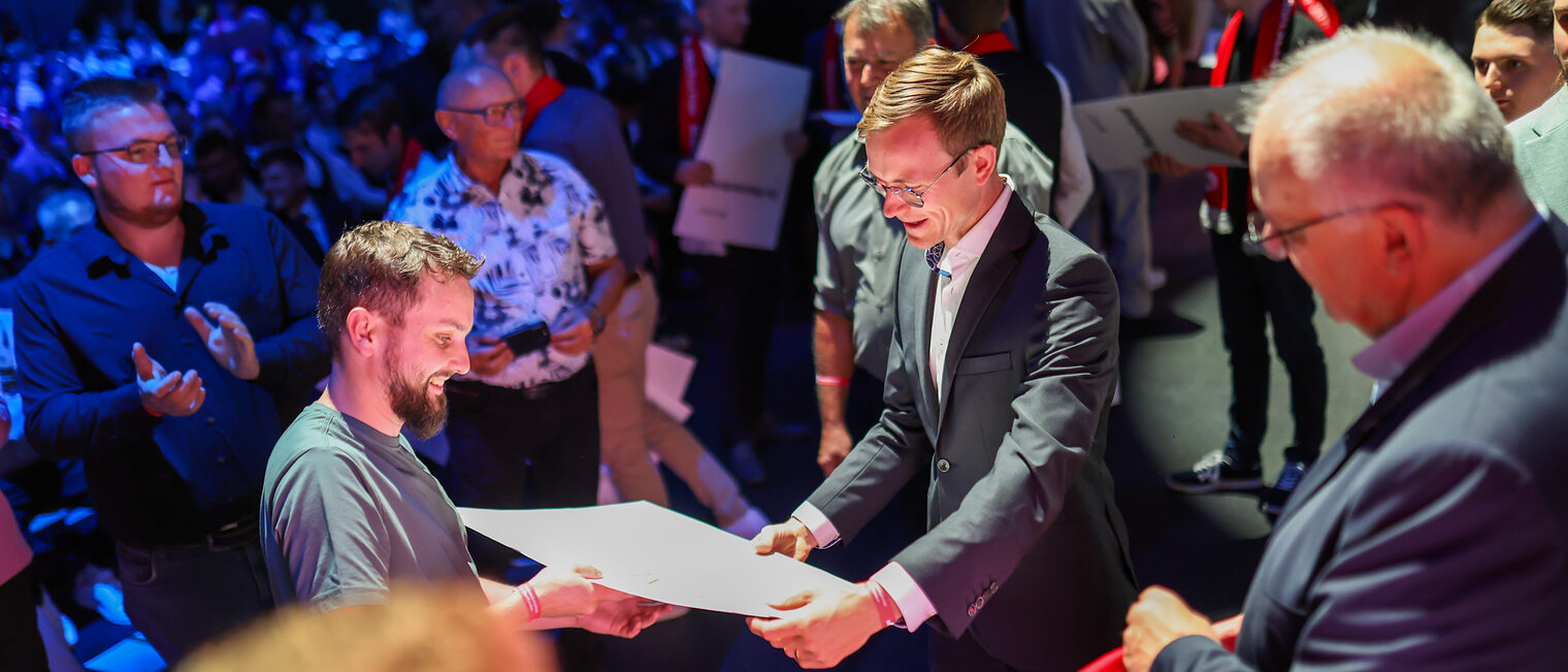Benedikt Doll übergibt einen Meisterbrief an einen Jungmeister.