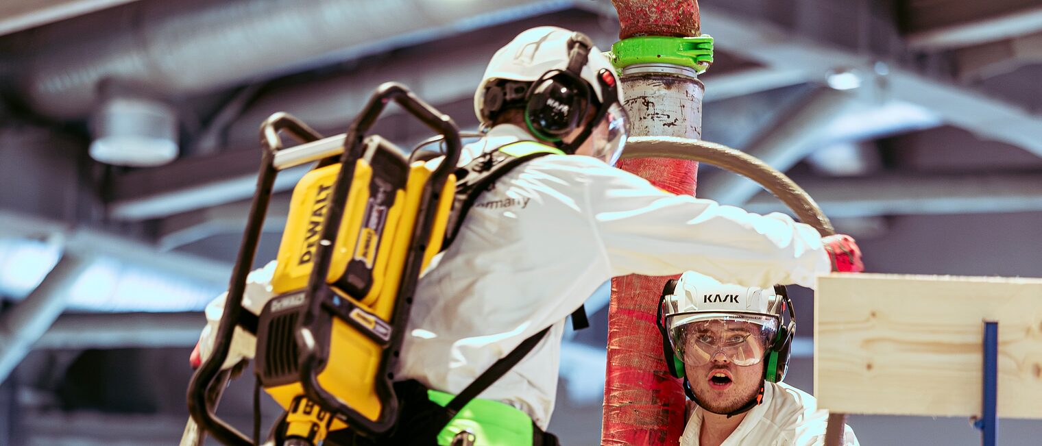 Jakob Distler und Tim Arnold gießen Beton über eine Leitung ein.
