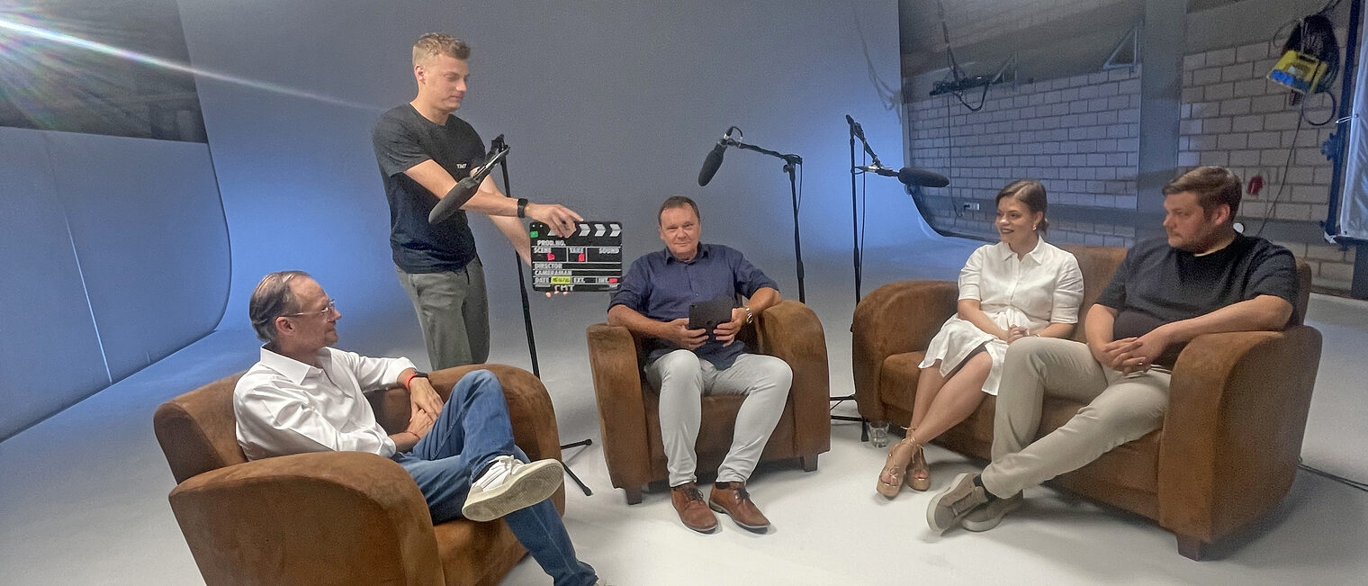 Andreas Fickenscher, Frank Ebert, Madlen Häckel und Domenik Alex sitzen während einer Aufnahme im Podcaststudio. 