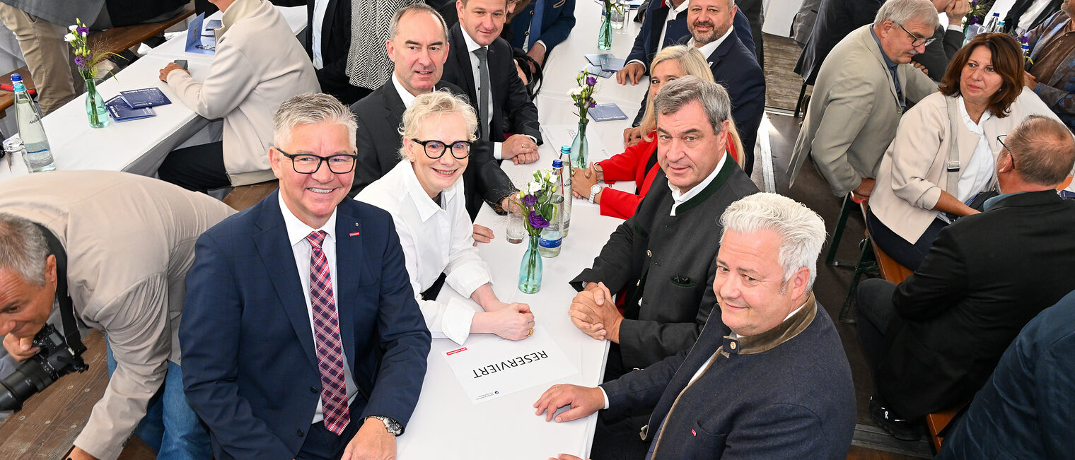 Matthias Graßmann, Christian Herpich, Petra Bahr, Markus Söder, Hubert Aiwanger und weitere Gäste sitzen in einem Zelt zusammen am Tisch.