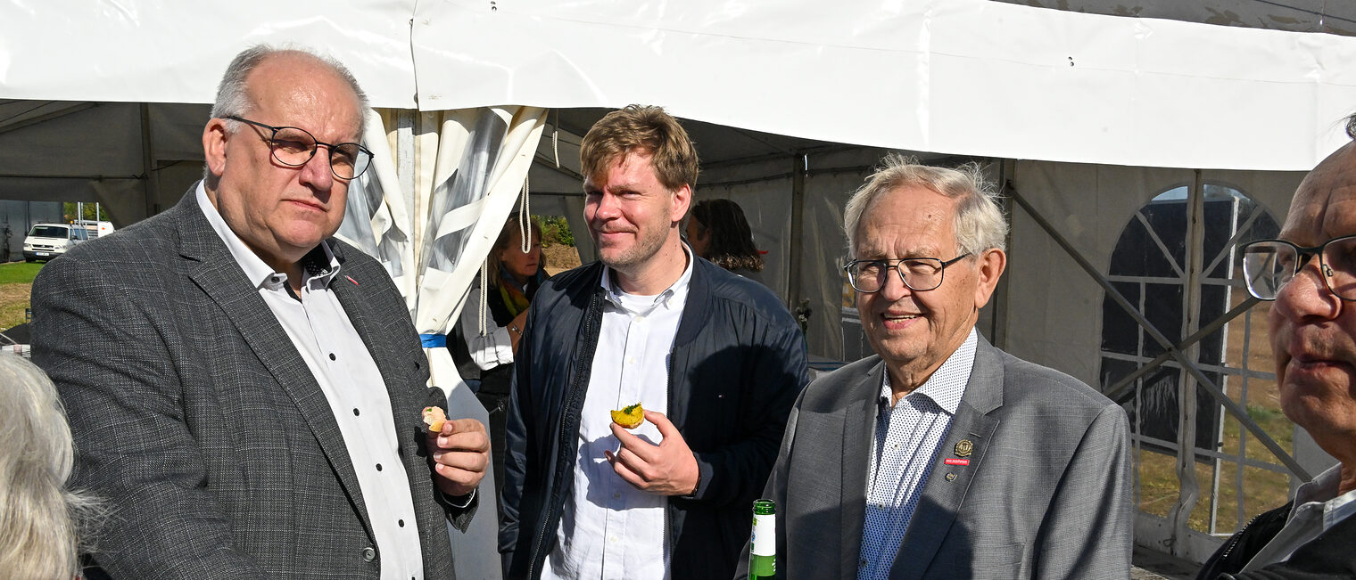 Reinhard Bauer und andere Mitglieder der Vollversammlung stehen an einem Stehtisch zusammen.