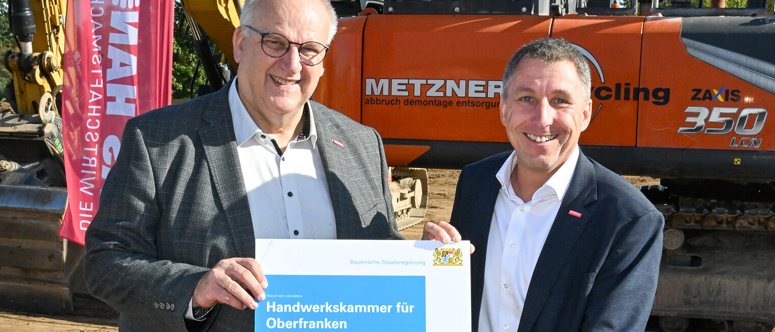Reinhard Bauer und Rainer Beck präsentieren den Förderbescheid der bayerischen Staatsregierung.