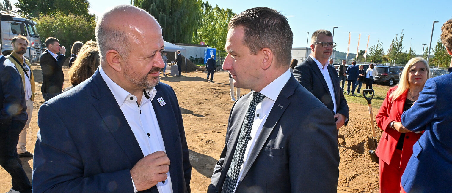 Zwei Gäste der Baustartfeier sprechen miteinander.