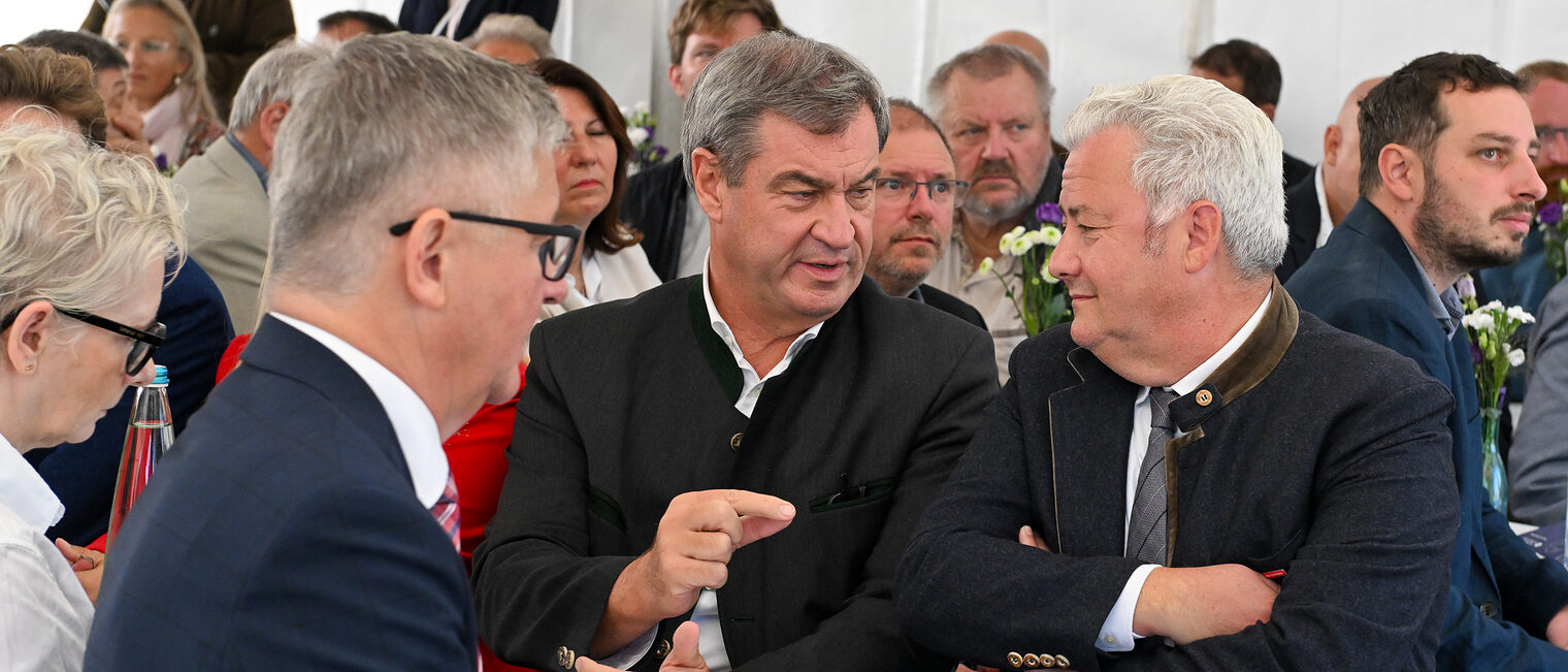 Markus Söder, Matthias Graßmann und Christian Herpich unterhalten sich an einem Tisch.