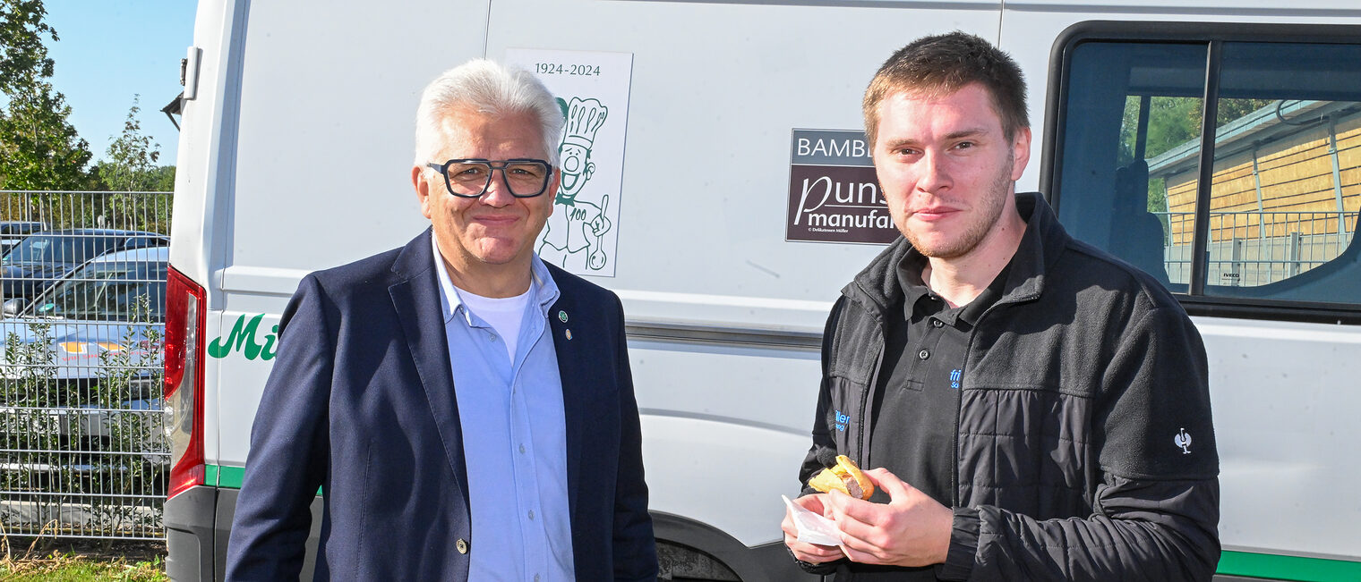 Leo Voran und ein weiterer Gast der Baustartfeier stehen vor einem Catering-Transporter.