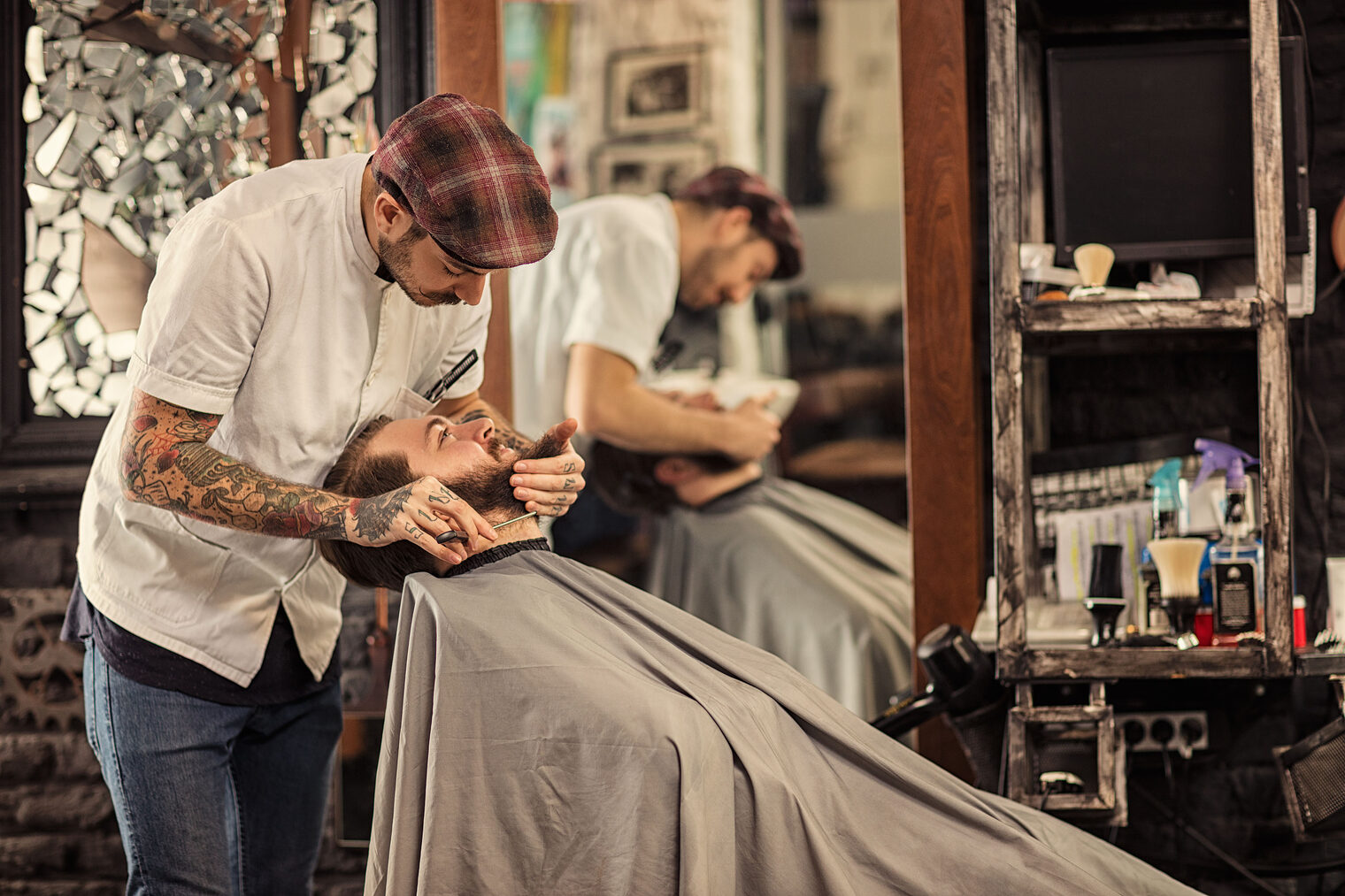 Ein Barber trimmt einem Kunden den Bart in einem Barbershop.