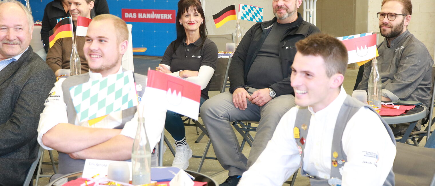 Tim Arnold und Jakob Distler sitzen an einem Tisch und lachen.