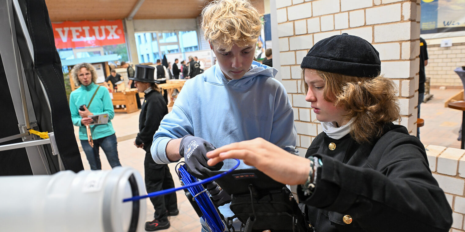Eine Jugendliche überprüft unter Anleitung Kabelverbindungen.