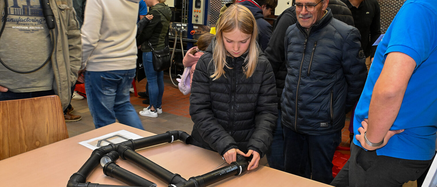 Eine Jugendliche setzt Rohrleitungen zusammen.