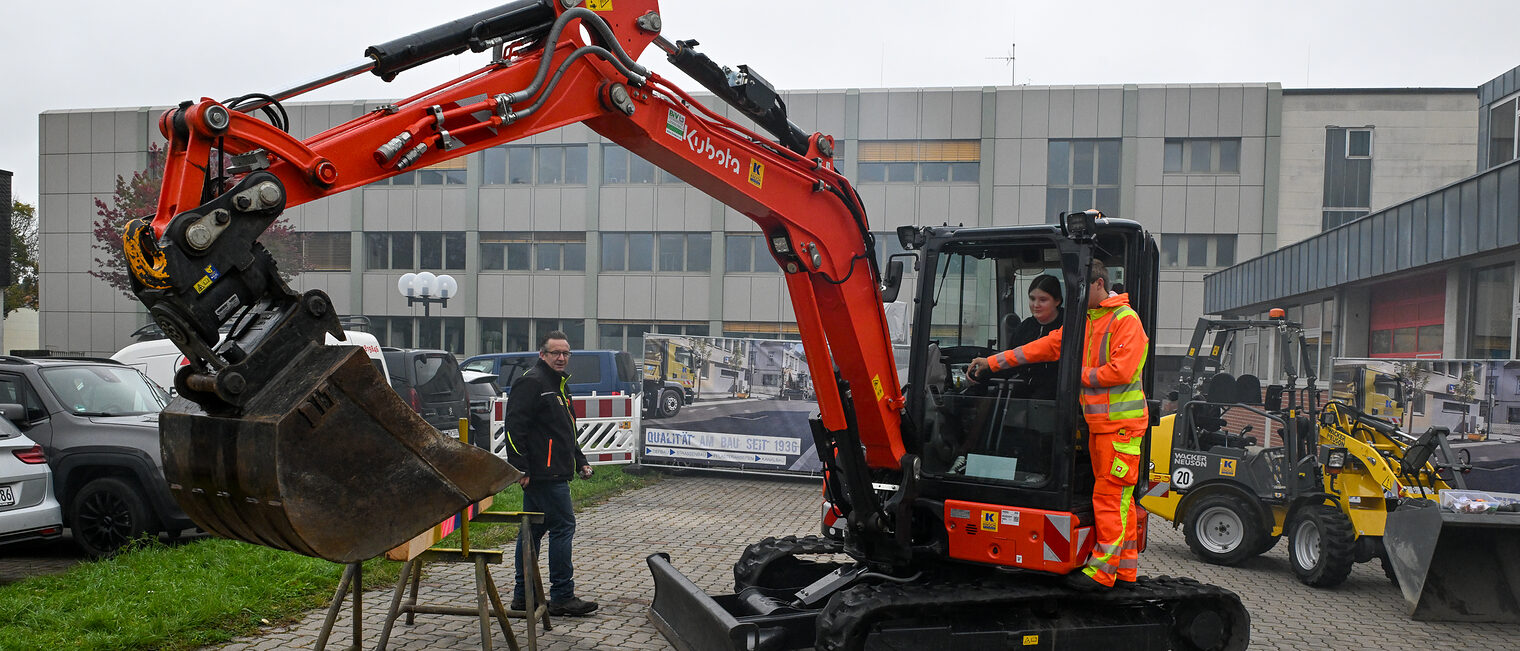 Ein Jugendlicher steuert unter Anleitung einen Bagger.