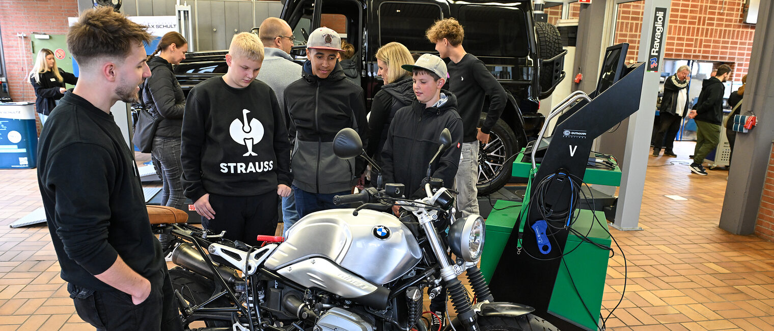 Mehrere Jugendliche sehen sich ein Motorrad an, dessen innerer Aufbau freigelegt ist. 