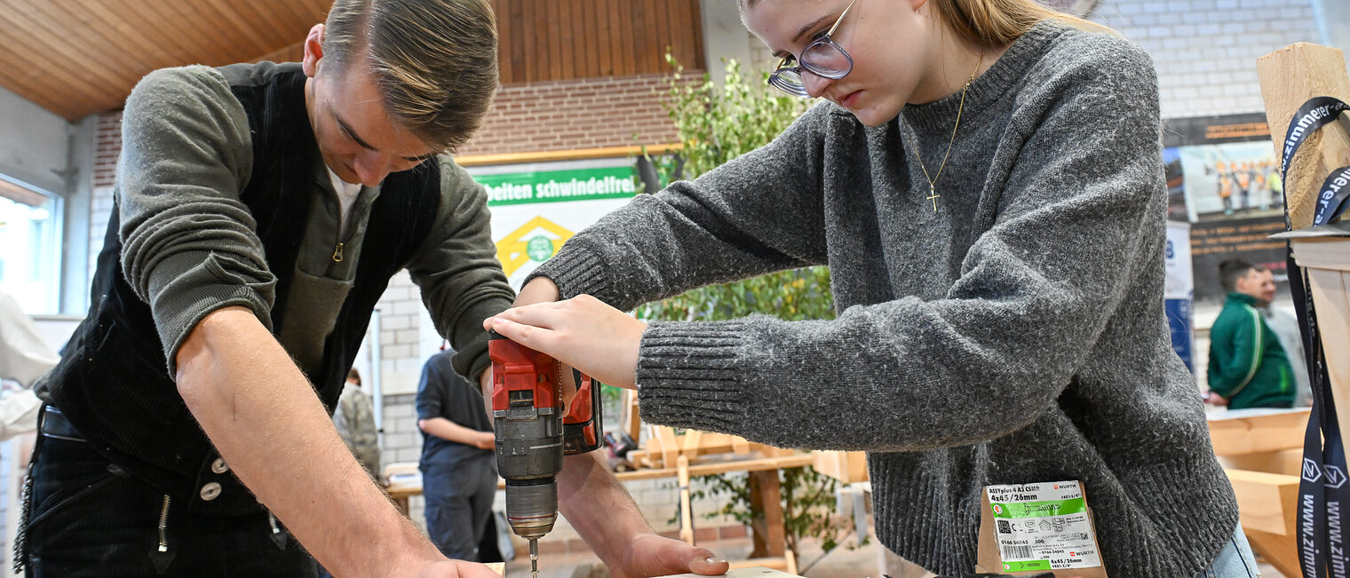 Eine Jugendliche bohrt eine Schraube in ein Holzbrett.