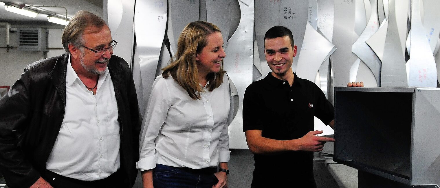 Der ungarische Bundessieger Balazs Kis (rechts) zeigt den Geschäftsführern Elke Rieß und Helmut Fuchs den Aufbau einer Luftkanaldämmung.