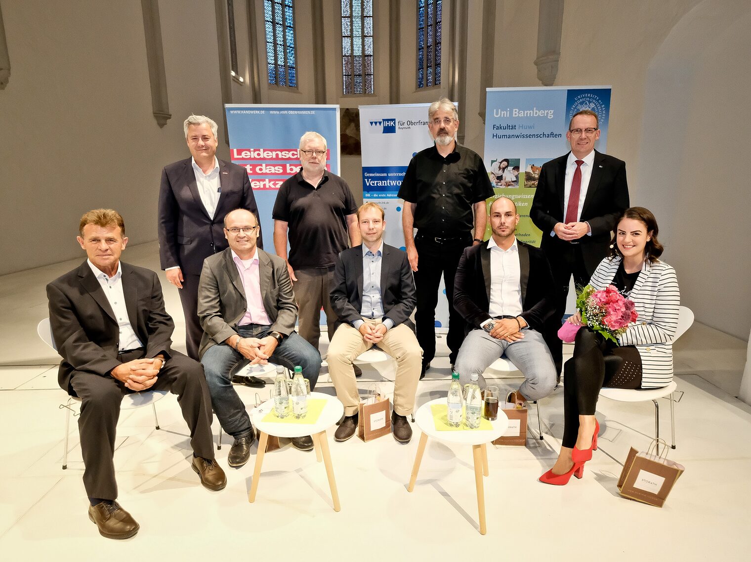 Die Veranstalter und das Podium der Tandemreihe zum Spitzensport: der Vizepräsident der Handwerkskammer für Oberfranken, Matthias Graßmann, der Präsident der Universität Bamberg, Prof. Dr. Dr. habil. Godehard Ruppert, der Vizepräsident für Technologie und Innovation an der Universität Bamberg, Prof. Dr. rer. nat. Guido Wirtz und Wolfram Brehm, Geschäftsführer der IHK für Oberfranken Bayreuth (obere Reihe von links), Prof. Dr. Stefan Voll, Erich Goldammer (Geschäftsführer der Bechert Technik & Service GmbH, Bayreuth), Jan Gorr (Trainer des HSC Coburg 2000), Deniz Bozkurt (Geschäftsführer der ONE MORE Dienstleistung GmbH, Bamberg) und Moderatorin Caroline Oberleiter von der IHK (untere Reihe von links).