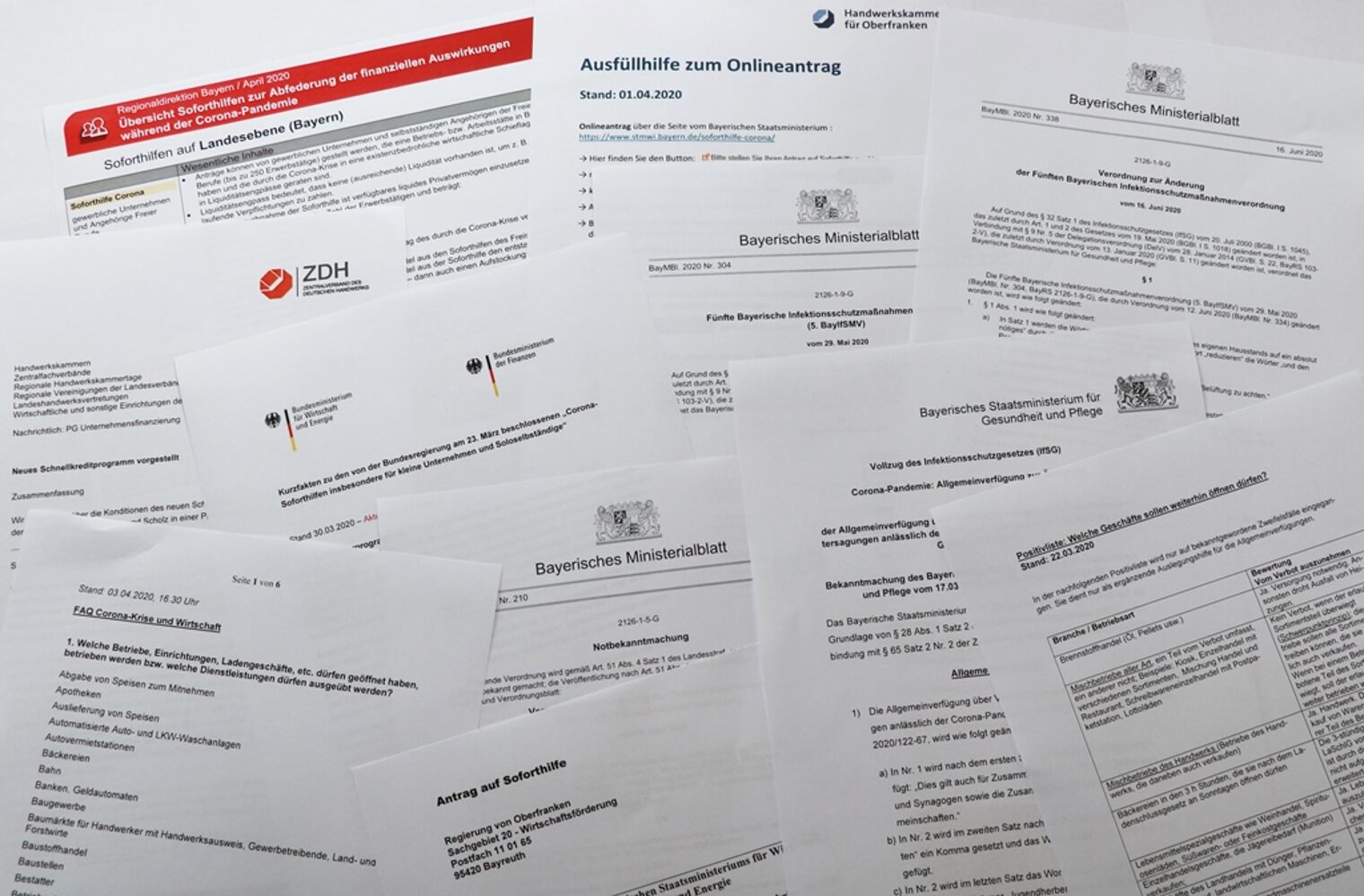 Eine Vielzahl an Dokumenten zur Beantragung von Finanzhilfen liegt auf einem Tisch.